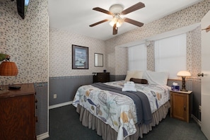 A bedroom with a bed, dresser, nightstand, and a ceiling fan. - Oyster Cove in Long Island Village (Port Isabel)