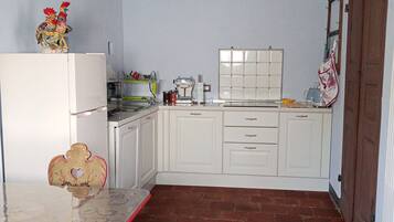 A kitchen with white cabinets, a red table, and a red chair.