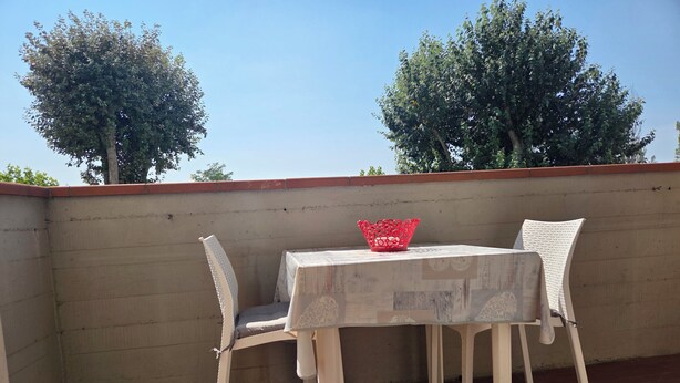 A small outdoor seating area with a table and two chairs, a red basket on the table, and a brick wall in the background. - Apartment 300 meters from the beach, with air conditioning and a private parking space (Lido Adriano)