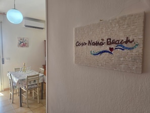 Uma sala de jantar com uma mesa posta para quatro, cadeiras e um lustre.