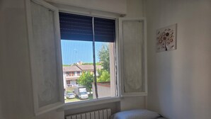 A bedroom with a window, a radiator, a bed, and a wall-mounted artwork. - Apartment 300 meters from the beach, with air conditioning and a private parking space (Lido Adriano)