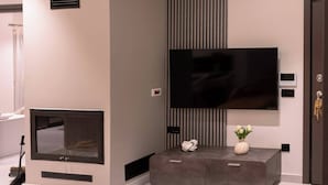 Ein modernes Wohnzimmer mit Fernseher an der Wand, einem Kamin und einem Konsolentisch mit Dekoration.