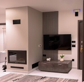 Un salon moderne doté d’un téléviseur à écran plat fixé au mur, d’une cheminée et d’une console sur laquelle sont disposés des objets décoratifs.
