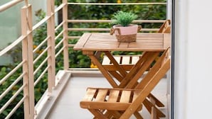 Ein Holztisch und Stühle auf einem Balkon mit einem Blumentopf.