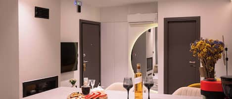 A modern hotel room with a central island featuring a wine bottle, glasses, and a fruit platter.