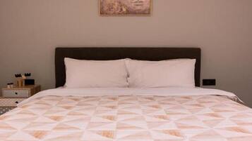 A bed with a geometric patterned bedspread, a dark headboard, and a wall-mounted artwork above it.