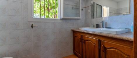 Un baño con inodoro, lavamanos y ventana con vistas a la vegetación.