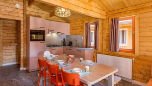 Een houten interieur met een keuken, een eettafel en oranje stoelen.