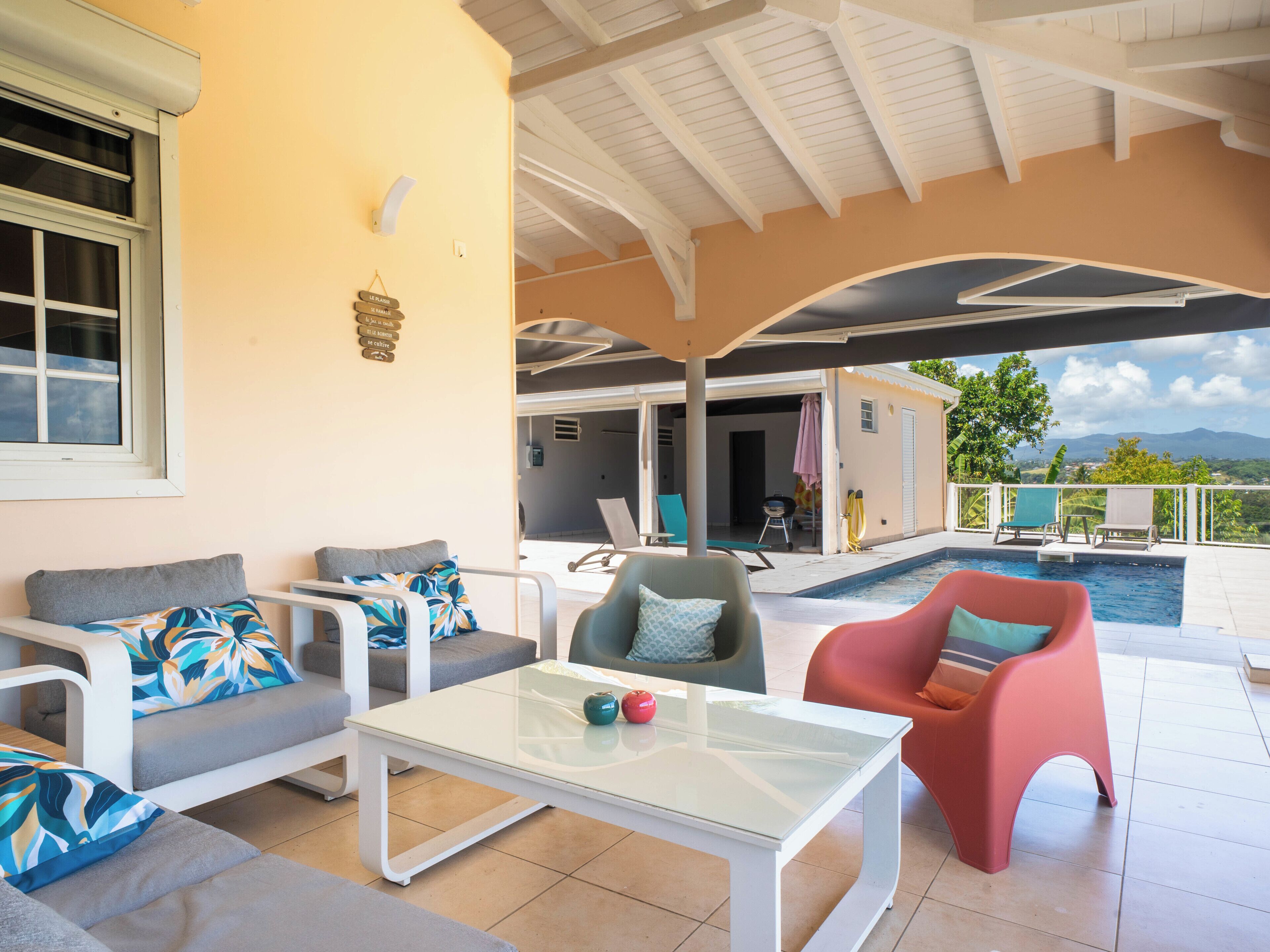 Un espace extérieur aménagé, abrité et doté d’une piscine, d’une table en verre et d’une vue sur le paysage.