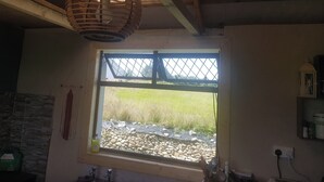 A kitchen with a window, a hanging light fixture, and a stone wall. - Tiny Living on the Wild Atlantic Way (Ballyduff)