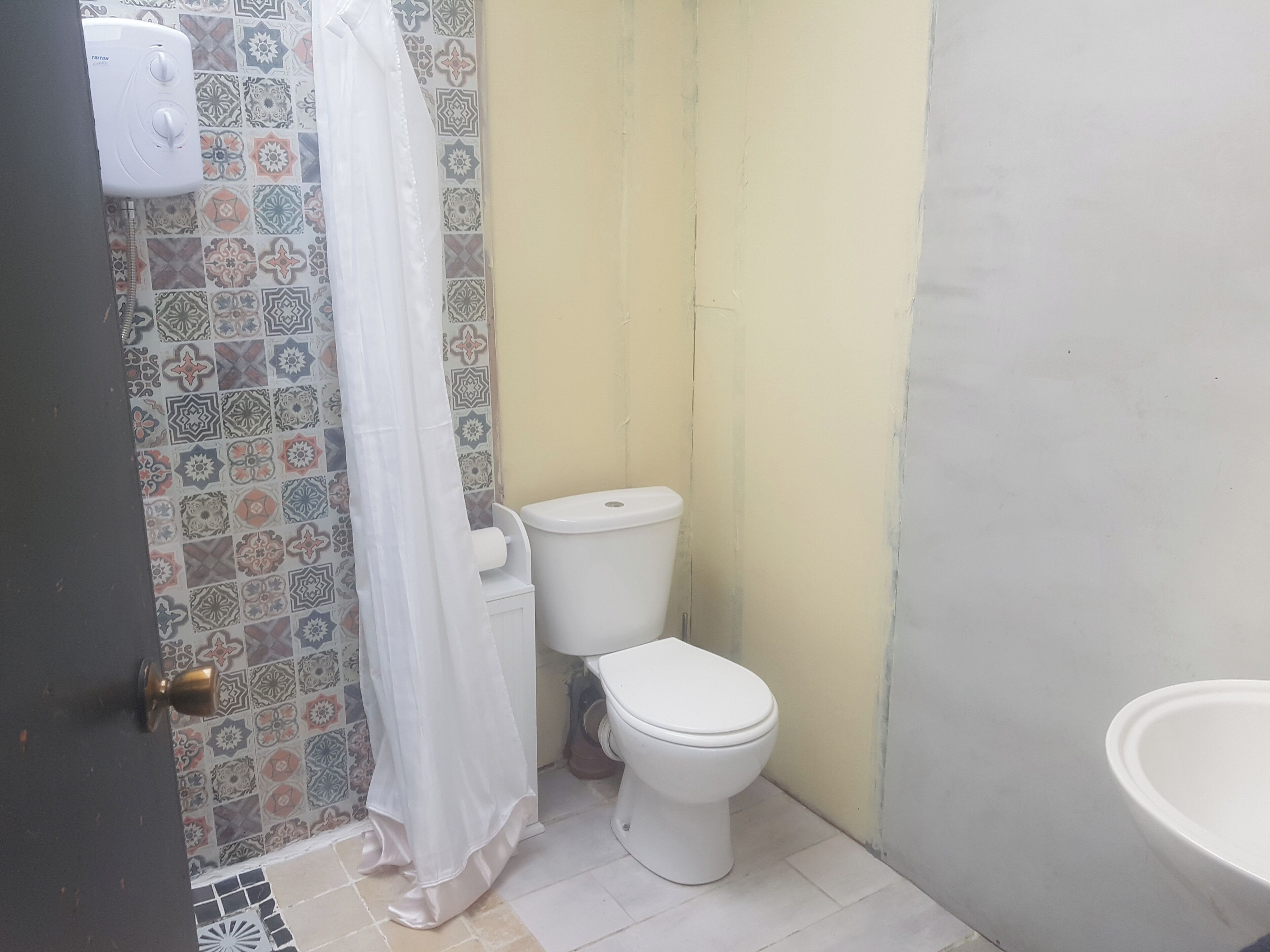 A small bathroom with a toilet, a shower curtain, and a toilet paper holder.