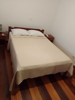 Una cama individual con cabecera de madera, una mesita de noche con lámpara y un teléfono.