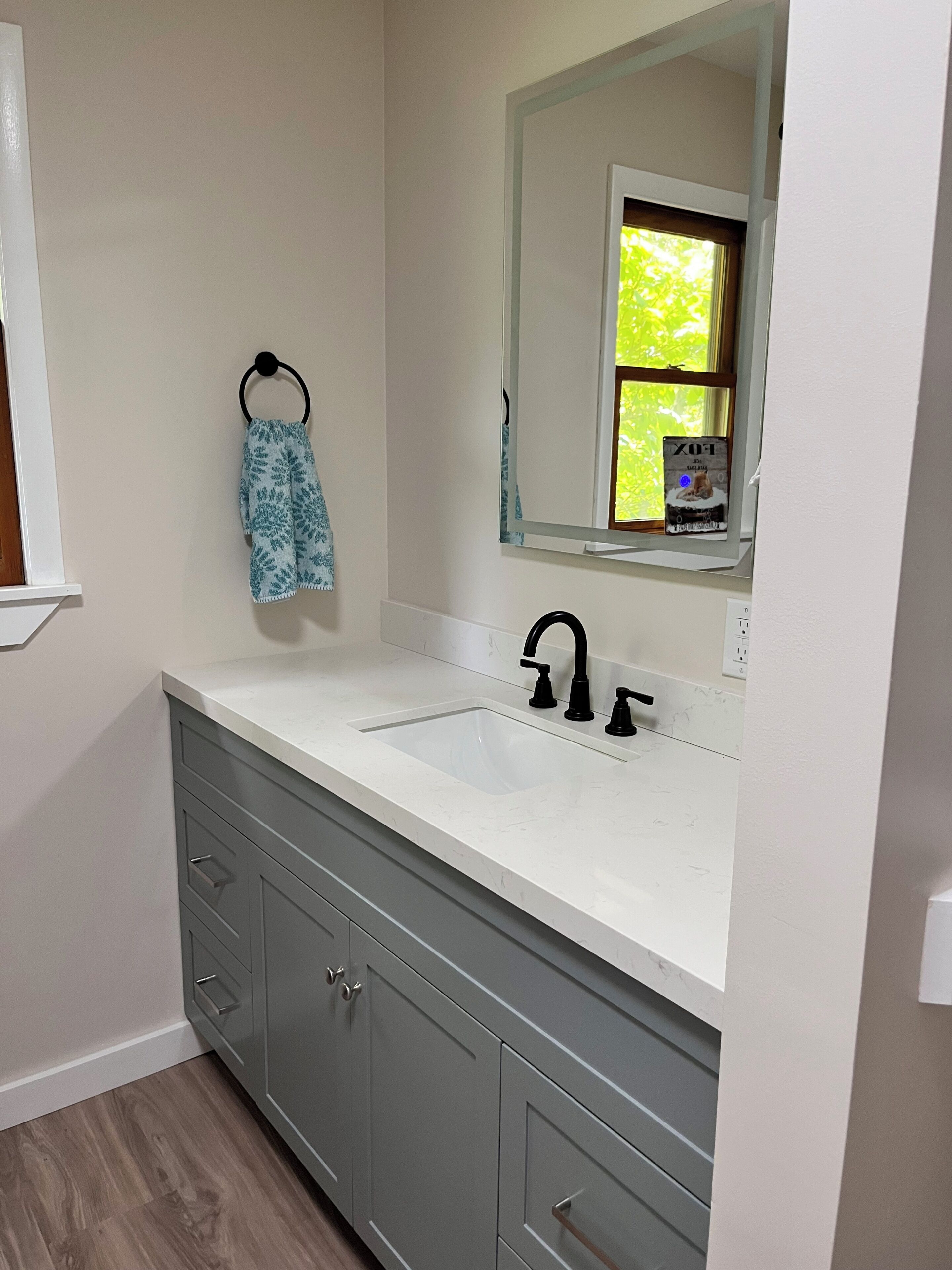 A bathroom with a white sink, a mirror, and a towel hanging on a hook.