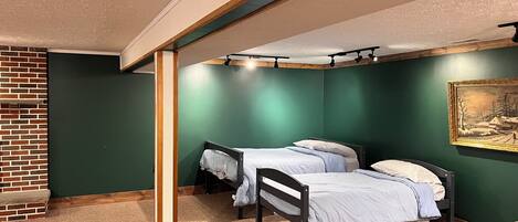 A room with two beds, a brick wall, and a green wall with a painting.