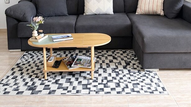 A modern living room with a grey sectional sofa, a wooden coffee table, and a checkered rug. There are two abstract paintings on the wall above the sofa. - Peaceful 2-Bedroom Apartment, Shared Pool, Balcony, Torrevieja, Alicante (Torrevieja)