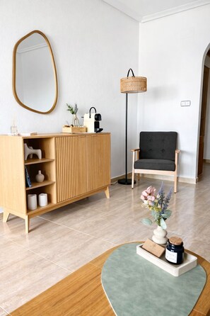 Un salon moderne avec un meuble en bois, un fauteuil noir, une lampe sur pied et une petite table sur laquelle est posé un vase.