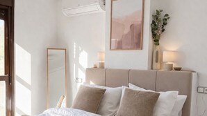 A bedroom with a bed, bedside tables, a ceiling fan, a wall-mounted air conditioner, a framed artwork, and a potted plant. - Peaceful 2-Bedroom Apartment, Shared Pool, Balcony, Torrevieja, Alicante (Torrevieja)