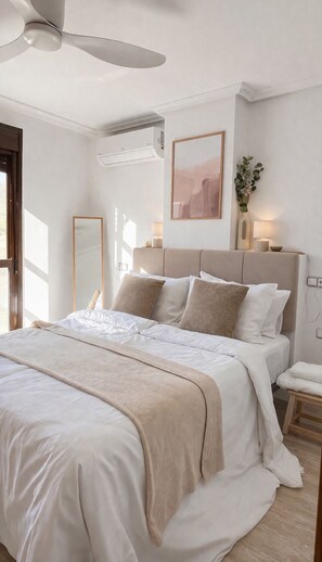 Quarto com cama, mesas de cabeceira, ventoinha no teto, ar-condicionado fixado na parede, obra de arte emoldurada e planta em vaso.