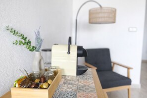 Uma cozinha com mesa de madeira, cafeteira, uma cadeira e um vaso com plantas.