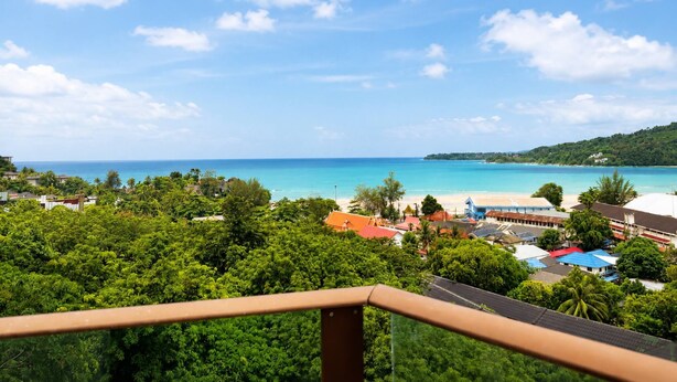 Blick auf die Küste mit klarem Himmel, Strand und Wohngebiet mit Häusern und Grünflächen.
