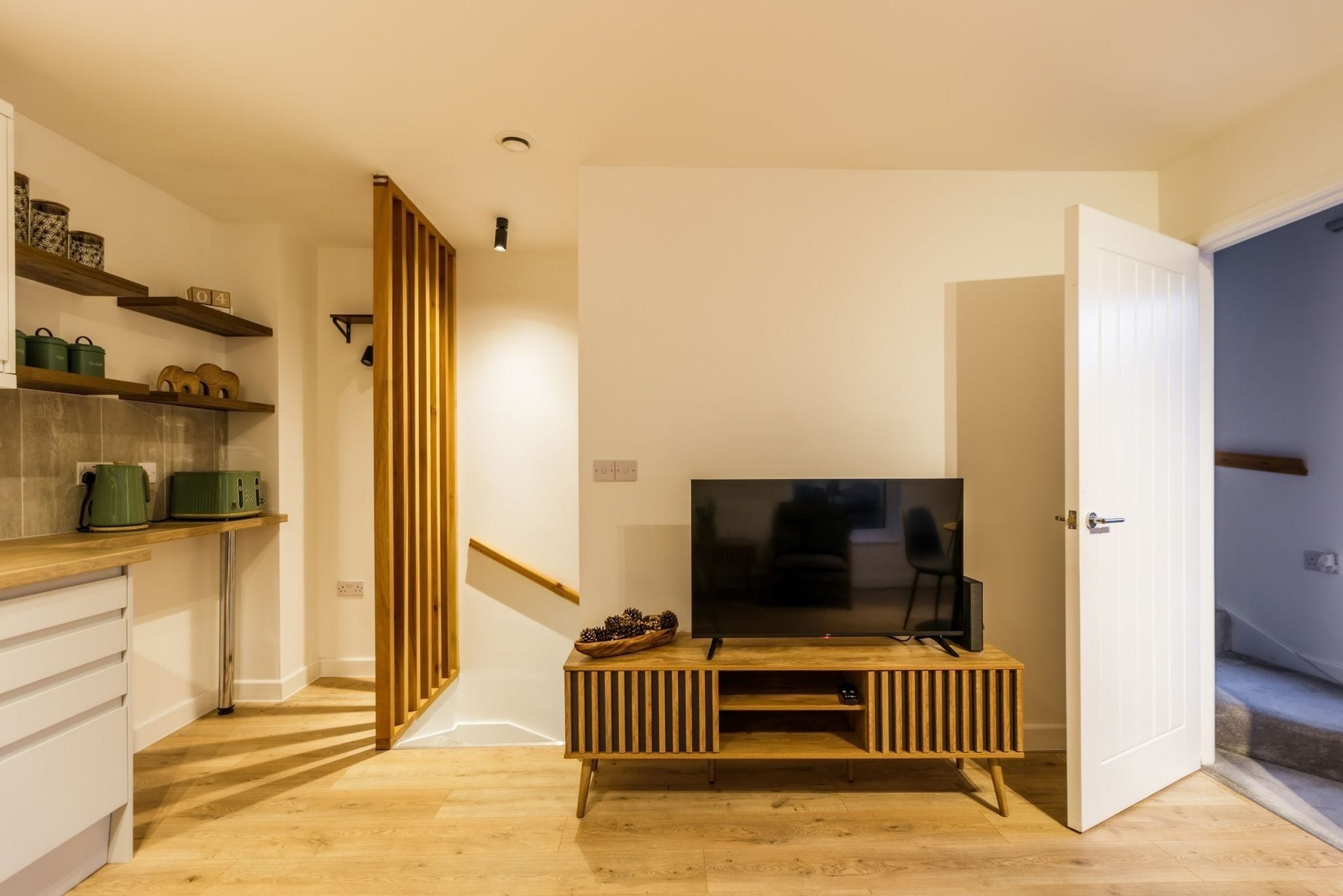 Een moderne keuken met houten kastjes, een ingebouwde televisie en een trap naar een ander niveau.