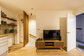 Una cucina moderna con mobili in legno, una TV integrata e una scala che conduce a un altro livello.