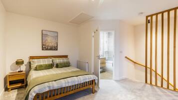 A bedroom with a bed, bedside table, lamp, and a painting on the wall.
