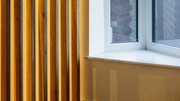 A corner of a room with a window, a wooden slat wall, and a carpeted floor.