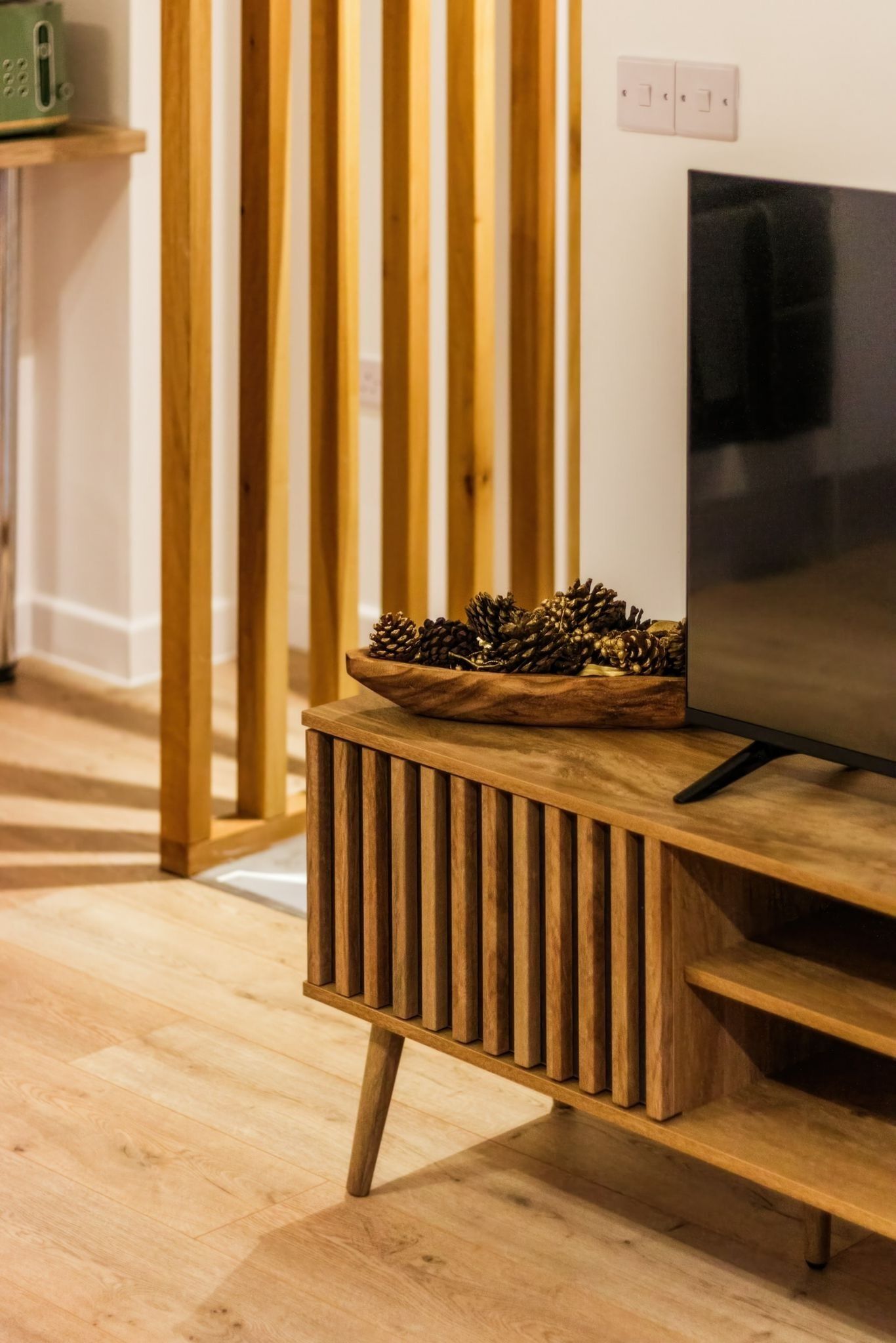 A wooden entertainment unit with a television and a pine cone decoration.