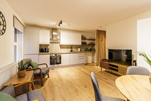Una cucina moderna con pensili bianchi, forno integrato e zona pranzo con tavolo e sedie in legno.