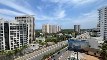 A multi-lane highway with vehicles, surrounded by high-rise buildings and greenery.