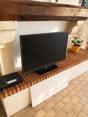 A flat-screen TV mounted on a brick wall with a white panel below. - Getaway in Touraine–House with a private courtyard (Bléré)