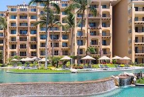 Un hôtel doté de nombreux balcons, d’une piscine avec une cascade et d’espaces de détente en plein air.