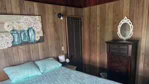 Ein Schlafzimmer mit einem Bett, einem Schminktisch, einem Spiegel und einer Wandleuchte.