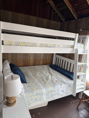 Ein Stockbett mit gemustertem Bettbezug, eine Nachttischlampe und ein Holzboden.