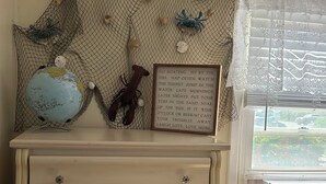 Ein Zimmer mit einem Schminktisch, einem Globus, einem Hummer und einem gerahmten Motivationsspruch.