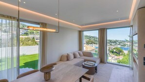 Ein modernes Wohnzimmer mit Essbereich, großen Fenstern und Blick auf eine Wohngegend.