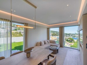 Ein modernes Wohnzimmer mit Essbereich, großen Fenstern und Blick auf eine Wohngegend.