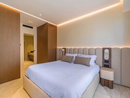 Un dormitorio moderno con una cama grande, un armario de madera y una mesita de noche.