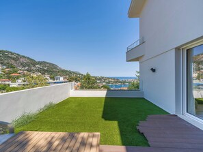 Ein moderner Balkon mit Blick auf eine Küstenstadt und eine Rasenfläche.