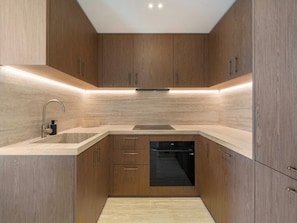 Eine moderne Küche mit Holzschränken, einer Edelstahl-Spüle und einem eingebauten Geschirrspüler.
