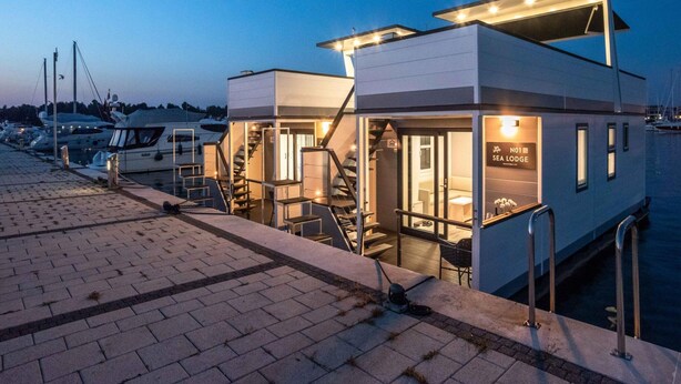 A waterfront property with a dock, a staircase leading to the upper level, and a sign indicating 'SEA LODGE'. - Dream Houseboat With a Whirlpool on the Water (Novigrad)