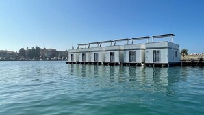 A floating hotel with multiple cabins, each with a balcony, docked at a waterfront. - Dream Houseboat With a Whirlpool on the Water (Novigrad)