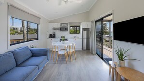 A modern kitchen with white cabinets, a dining table, and a built-in oven. - Reflections Holiday Park Forster Beach (Forster)