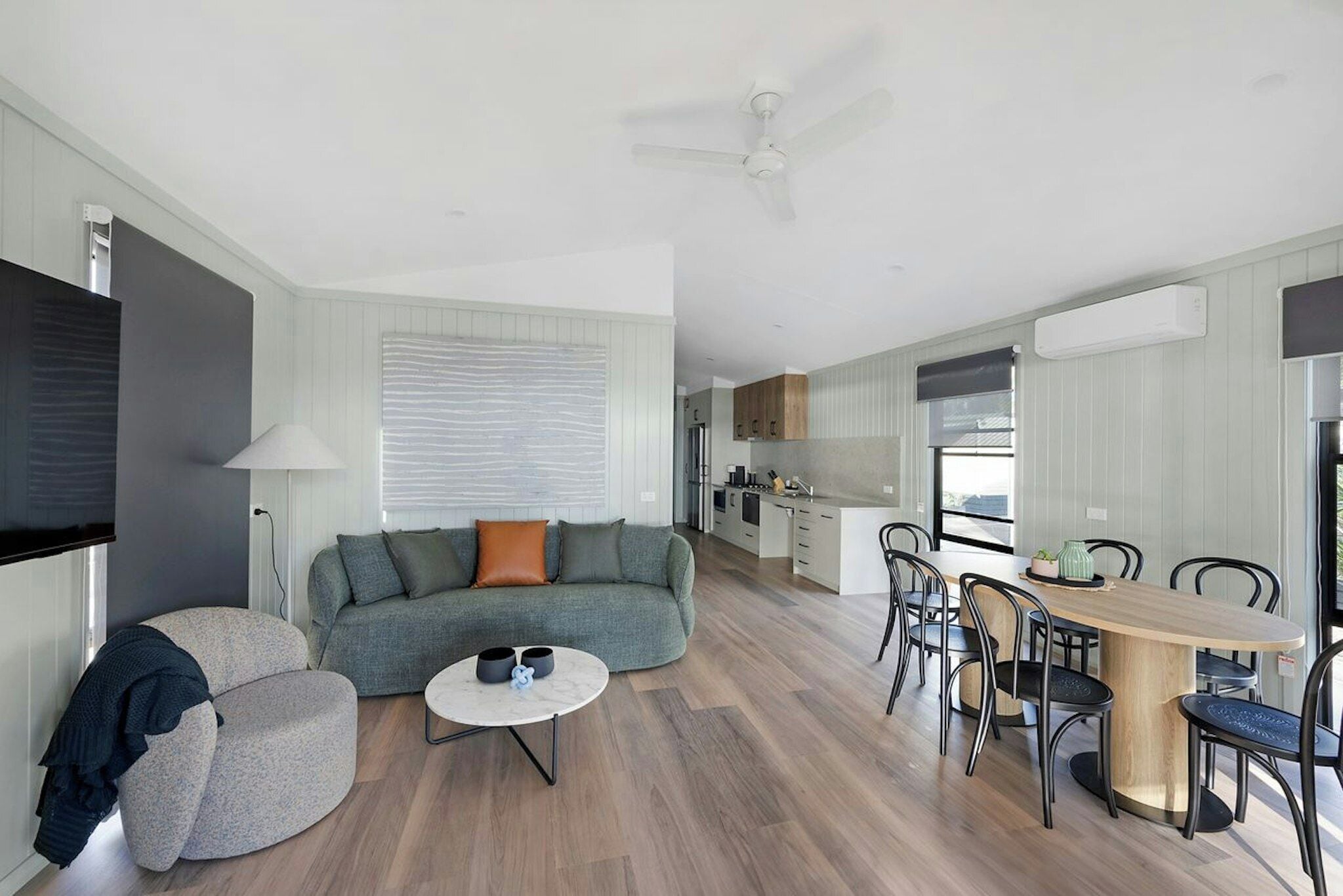 Een moderne woonkamer met een bank, een salontafel en een eethoek met stoelen en een tafel.