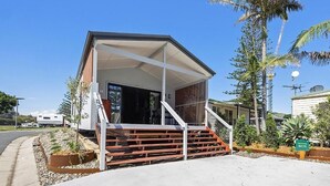 A modern building with a covered entrance, a staircase, and a parking area with a sign indicating a specific location. - Reflections Holiday Park Forster Beach (Forster)