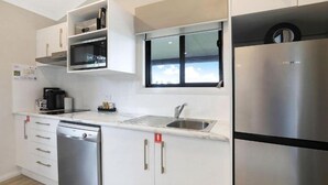A modern kitchen with stainless steel appliances, a dishwasher, and a window above the sink. - Reflections Holiday Park Forster Beach (Forster)