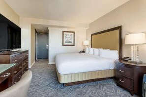 Ein Hotelzimmer mit Bett, Schreibtisch, Stuhl, Fernseher und Spiegel.