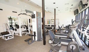 Ein Fitnessstudio mit Cardiogeräten, Krafttrainingsgeräten und Kurzhanteln.