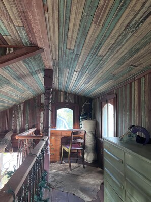 A rustic cabin interior with a wooden desk, a chair, a dresser, and a window with a view of greenery. - Cottage on Exotic Animal Ranch -- Weekend Retreat in Texas Hill Country (Driftwood)